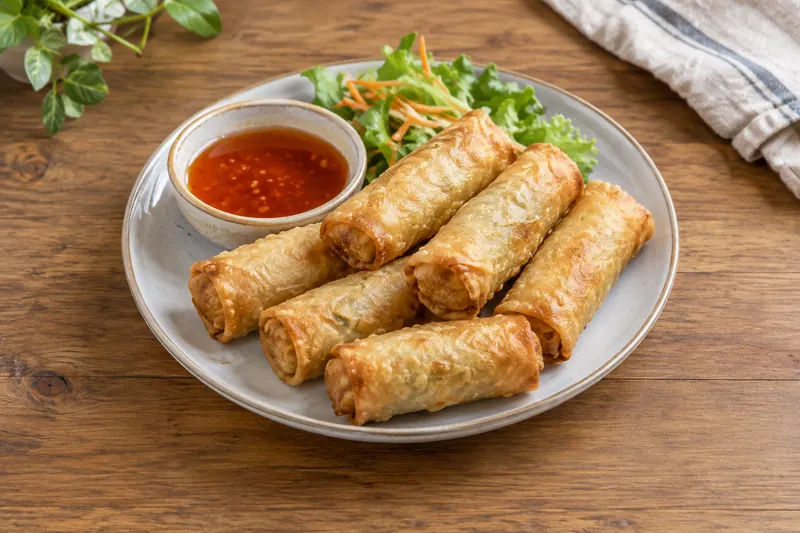 Golden Chinese spring rolls stacked on a plate